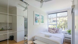 A modern bedroom with a bed, a desk, a window, and a ceiling fan. - Delightful Darling Point Studio w Stunning Rooftop (Darling Point)