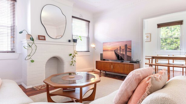 A living room with a fireplace, a round coffee table, a sofa, and a television.