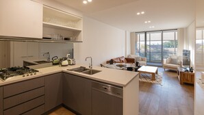 Una cocina moderna con una isla central, electrodomésticos integrados y un comedor con sofá y mesa de centro.