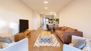 Una sala de estar moderna con un televisor de pantalla plana, una mesa de centro de madera y un sofá.
