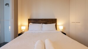 Una habitación de hotel con una cama grande, dos lámparas de noche, un cabecero de madera y un armario.