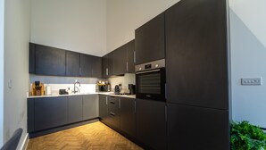 A modern kitchen with dark cabinets, a built-in oven, and a herringbone wood floor.