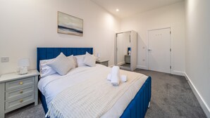 A bedroom with a bed, nightstands, a mirror, and a door.