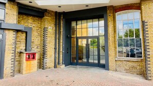 A building entrance with a glass door, brick walls, and a red mailbox.
