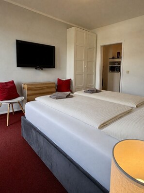 Une chambre d’hôtel avec un grand lit, une télévision, une armoire et une petite table avec une chaise.