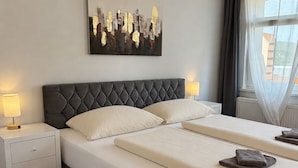 A hotel room with a large bed, two bedside tables, a wall-mounted artwork, and a window with curtains. - apartment for 4 people with kitchen & balcony, view of the Elbe & free Wi-Fi (Dresden)