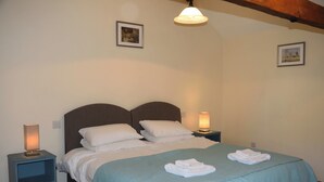 Ein ordentlich gemachtes Bett mit weißen Leinen, zwei Nachttischlampen und einer blauen Tagesdecke.