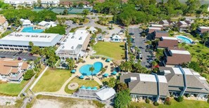 An aerial view of a resort with multiple buildings, a large swimming pool, and surrounding greenery. - 313 Ocean Point Drive (Fripp Island)
