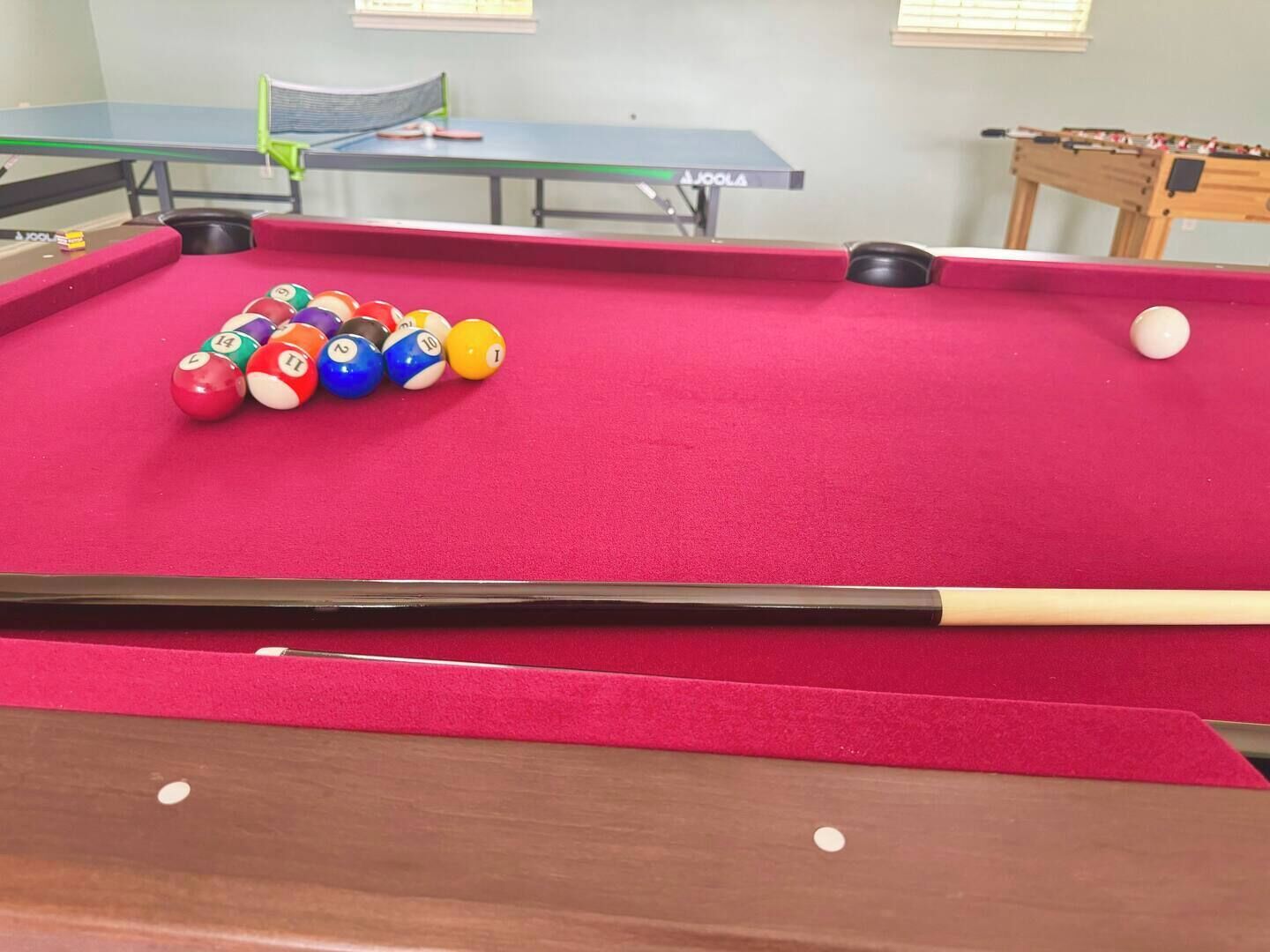 A pool table with billiard balls and a cue stick.