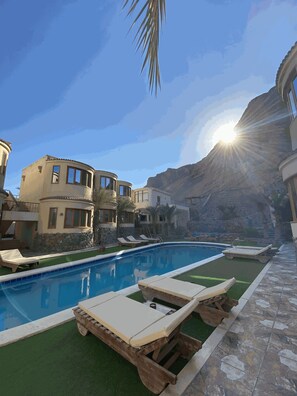 A pool area with lounge chairs, a swimming pool, and a mountainous backdrop. - Neptune Residence Dahab (Dahab)