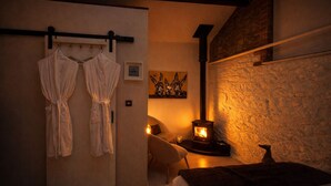 Une pièce confortable avec un lit, une chaise, une cheminée et un porte-peignoir.