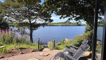 A lakeside view with a gazebo, outdoor seating, and a gravel path.
