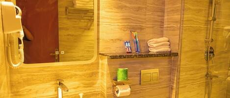 Casa de banho moderna com lavatório de mármore, cabine de duche com vidro e espelho com reflexo de uma porta vermelha.