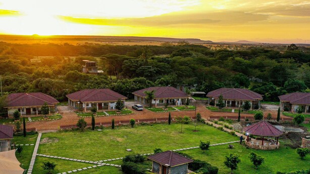 A residential area with multiple houses, each with a red roof, surrounded by greenery and a clear sky. - Olakira Mara Homes (Maasai Mara)