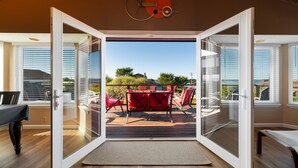 An open sliding glass door leading to a deck with red furniture and a view of the outdoors. - Welcome to 'Ocean Oasis' Located on Park Hill in Cambria! (Cambria)