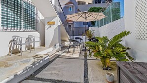 Une cour avec des sièges en plein air, un pot de fleurs et un escalier menant à un niveau supérieur.