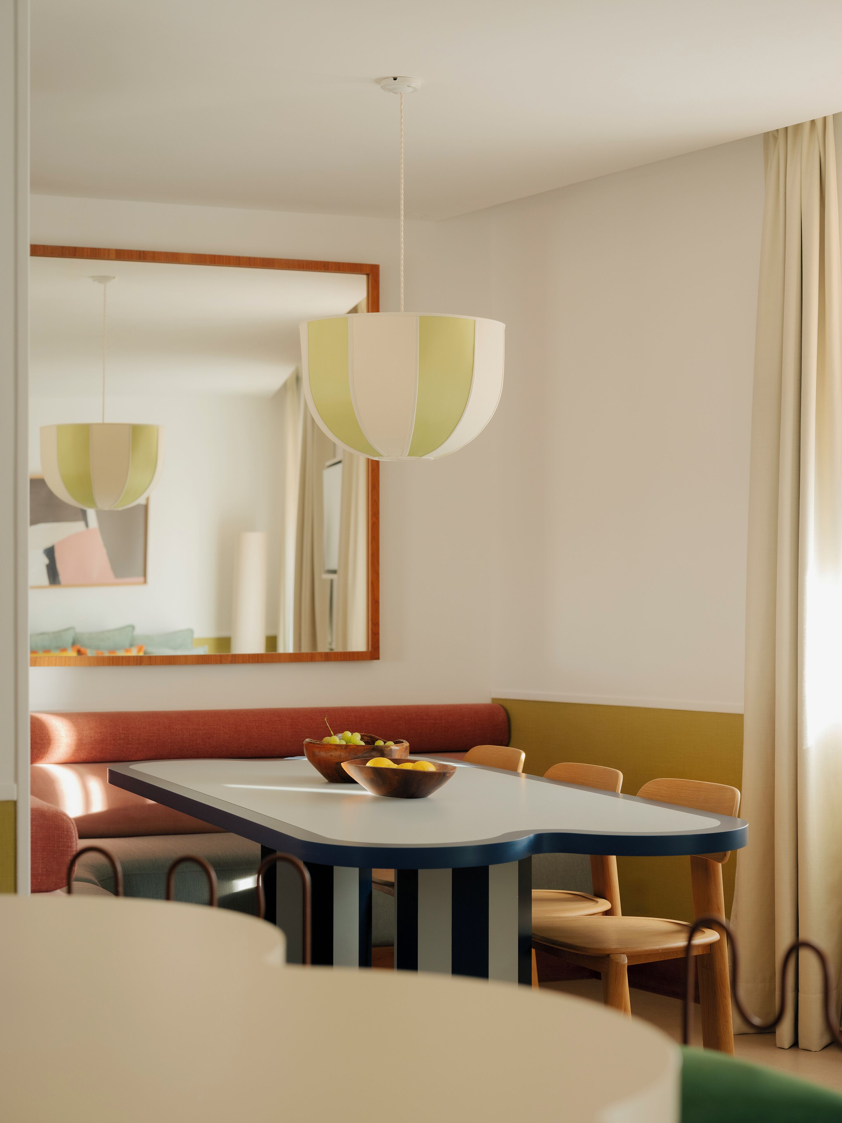 A dining area with a table, chairs, and a bowl of fruit.
