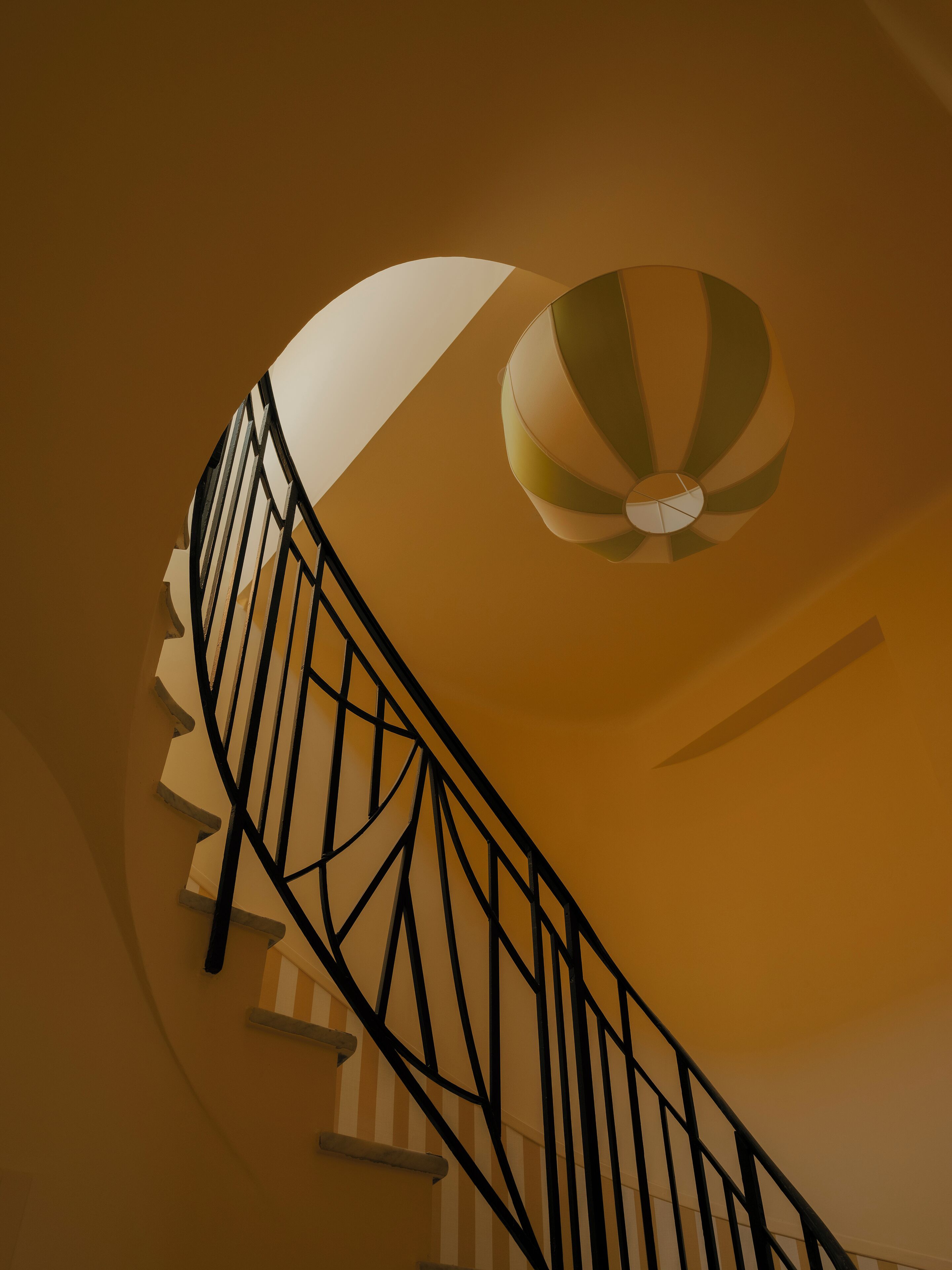 A spiral staircase with a black railing and a ceiling fan.