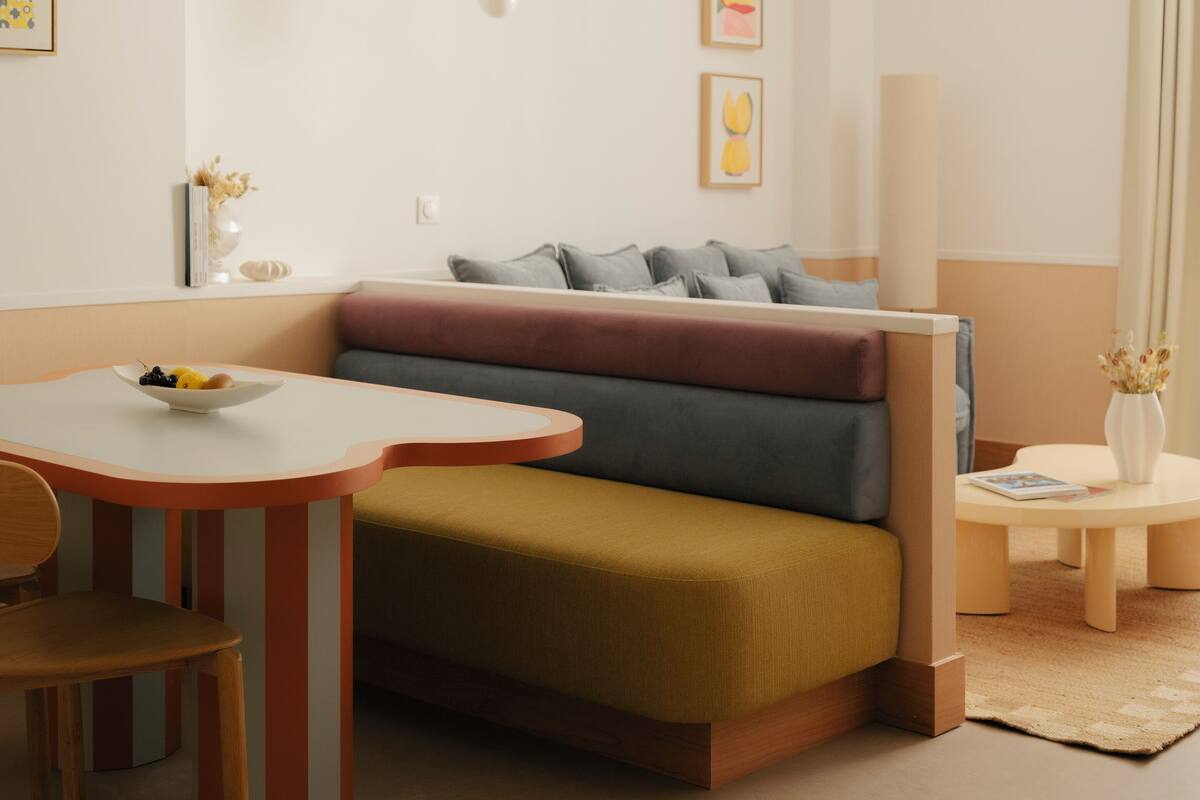A modern living room with a sofa, a dining table, and a hanging light fixture.