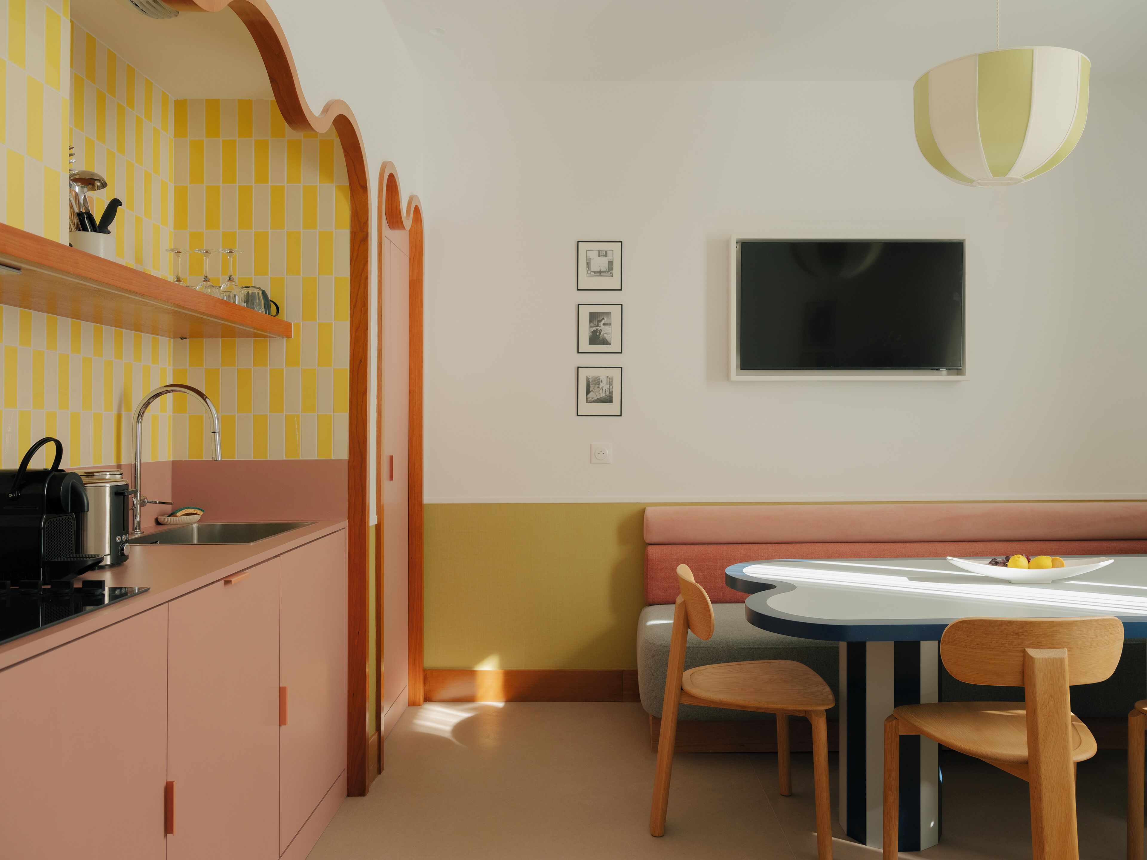 A modern kitchen with a checkered backsplash, a built-in oven, and a dining area with a round table and chairs.
