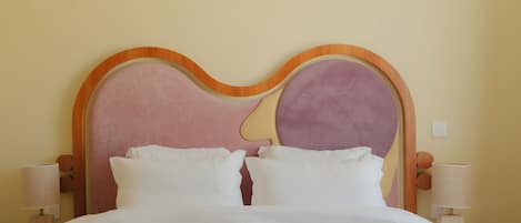A bed with a wooden headboard, two bedside tables with lamps, and a wall-mounted light switch.