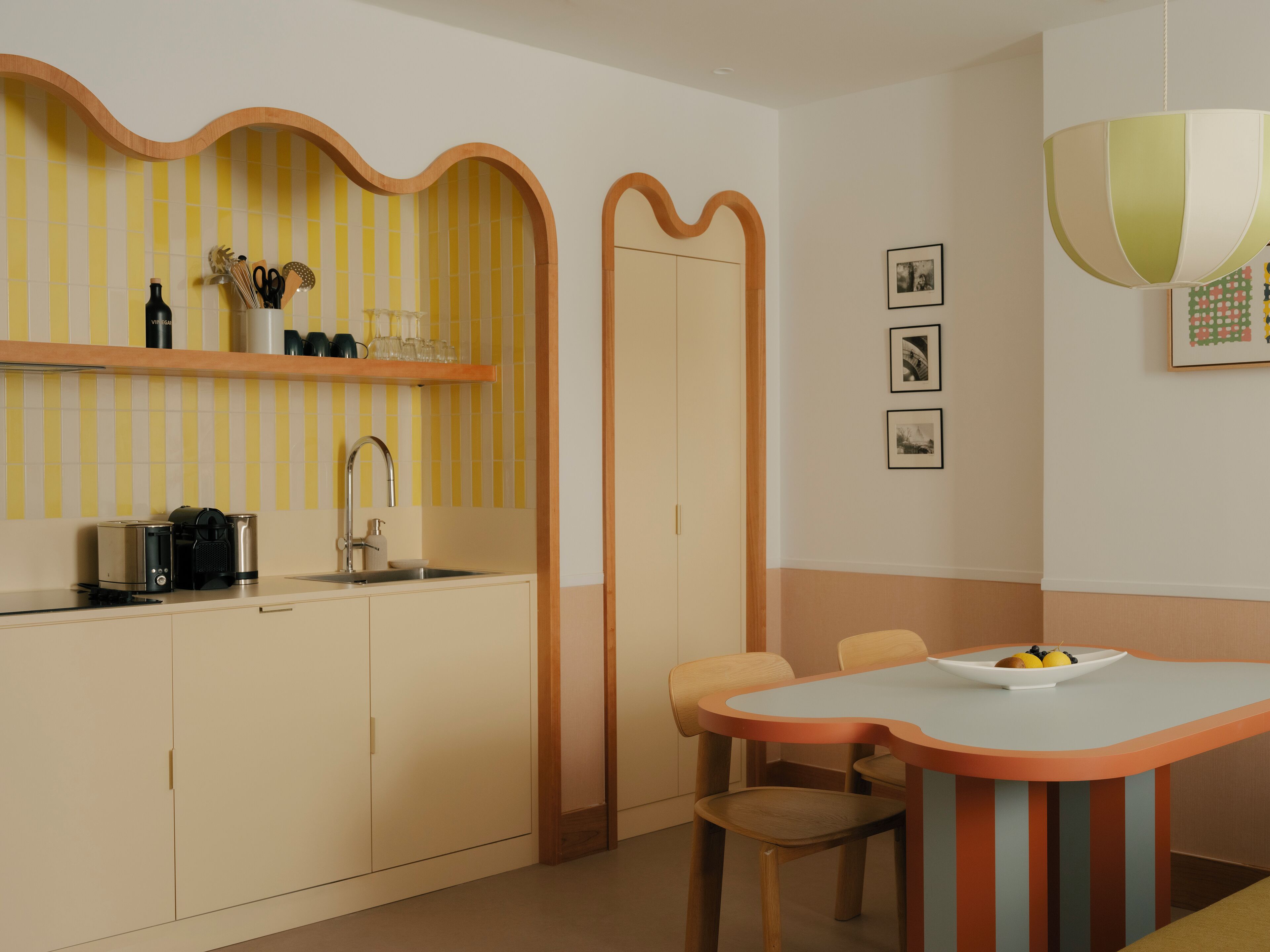 Une cuisine moderne équipée d’un four encastré, d’un évier et d’un coin repas avec une table et des chaises.
