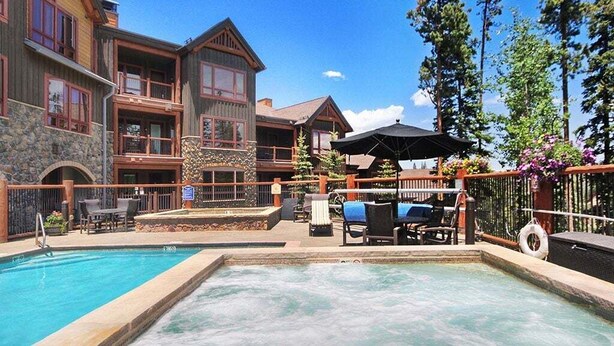 A pool area with a hot tub, lounge chairs, and a wooden deck. - Bluesky 414: Ski-In/Out Peak 9, Private Hot Tub & Fireplace, Shuttle. (Breckenridge)