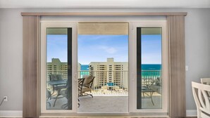 A room with a sliding glass door leading to a balcony with a view of the ocean and buildings. - Ocean View 1BR 2BA @ Fully Loaded Resort! (Panama City Beach)
