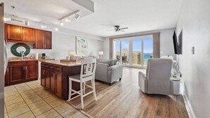 A spacious living area with a kitchen, a balcony with a view of the ocean, and a ceiling fan. - Ocean View 1BR 2BA @ Fully Loaded Resort! (Panama City Beach)