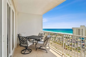 Enjoy the ocean view from this balcony with a table and two chairs.