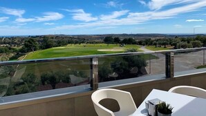Un balcone con vista su un campo da golf, un tavolo e due sedie.