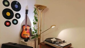 Una habitación con una guitarra, un tocadiscos y discos de vinilo en la pared.
