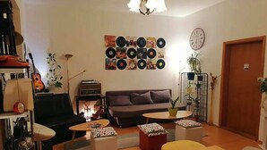 Una sala de estar acogedora con un sofá, una mesita de centro, otomanas y una pared decorada con discos de vinilo.