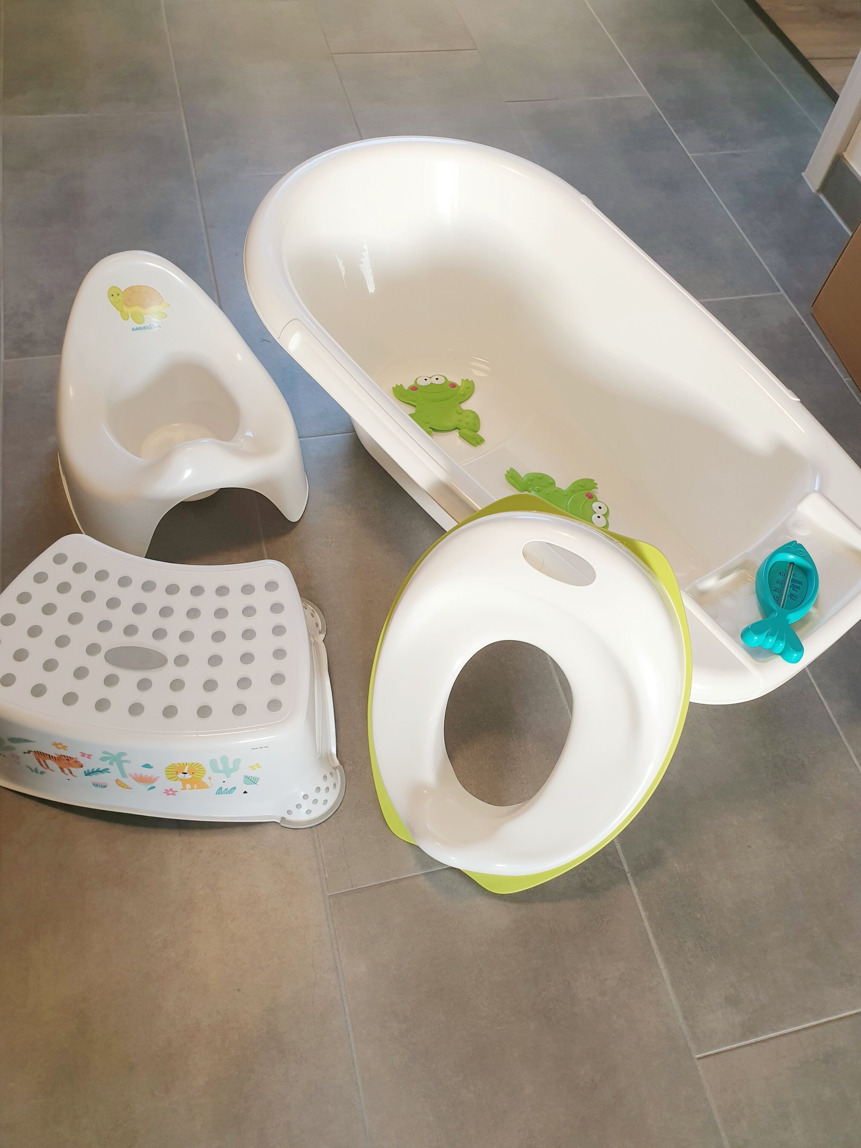 Un baño con bañera para bebé, un orinal para niños pequeños y un taburete.