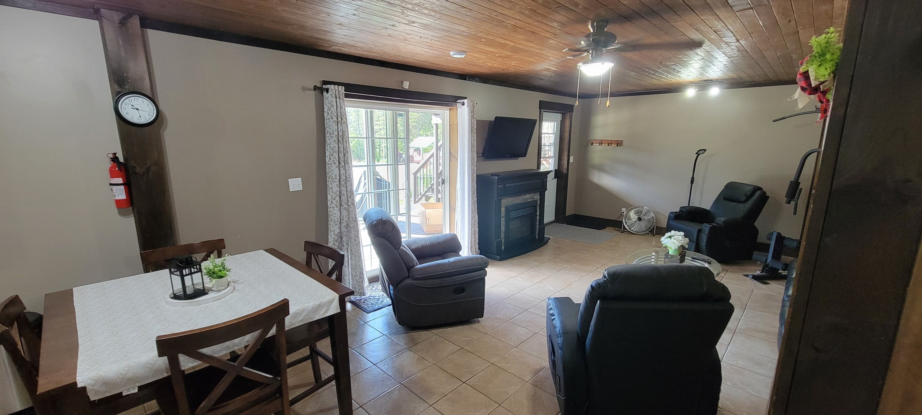 Ein Wohnzimmer mit Kamin, einer Essecke mit Tisch und Stühlen sowie einer Sitzecke mit Sofa und Sesseln.