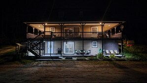 Een tweelaags huis met een balkon, een overdekte veranda en een trap die naar de bovenverdieping leidt.