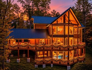 Une cabane en bois à plusieurs niveaux, dotée d’un balcon et entourée d’arbres.