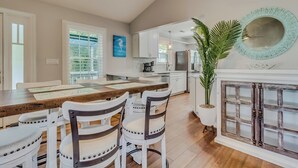 A spacious kitchen with white cabinetry, a wooden dining table, and a large mirror above the fireplace. - Raised Beach house/Golf Cart/Hot tub/Arcade/BAR/Pool table (Myrtle Beach)