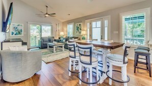 A spacious living room with a wooden dining table, white chairs, and a grey sofa. There are ceiling fans and a TV mounted on the wall. - Raised Beach house/Golf Cart/Hot tub/Arcade/BAR/Pool table (Myrtle Beach)