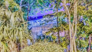 A lush garden with a white fence and a building in the background. - Raised Beach house/Golf Cart/Hot tub/Arcade/BAR/Pool table (Myrtle Beach)