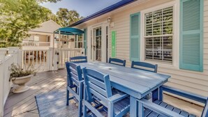 A covered patio with a wooden table and chairs, a white fence, and a green 'WELCOME' sign. - Raised Beach house/Golf Cart/Hot tub/Arcade/BAR/Pool table (Myrtle Beach)