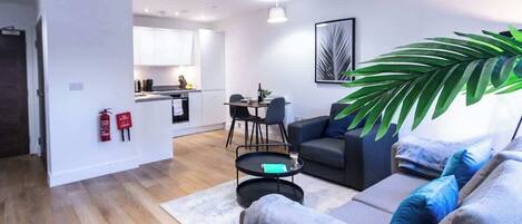 Una sala de estar moderna con un sofá gris, una mesa de centro y una planta verde grande.