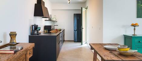 A modern kitchen with a central island, a dining table, and a teal cabinet.