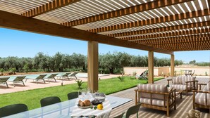 An outdoor patio with a glass table, chairs, and a pool area. - Villa with Pool and A/C in Sicily (Menfi)