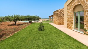 A modern building with stone walls and a well-maintained lawn. - Villa with Pool and A/C in Sicily (Menfi)