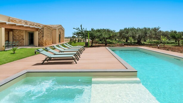 A swimming pool with lounge chairs and a building with stone walls. - Villa with Pool and A/C in Sicily (Menfi)