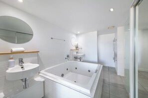 A modern bathroom with a large bathtub, a sink, a mirror, and a glass shower enclosure. - Luxury Oceanview Apartment | 2 Bedrooms | 2 Ensuites | Resort Pool (AIRLIE BEACH)