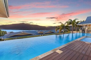 A swimming pool with a view of a mountain and a sunset.