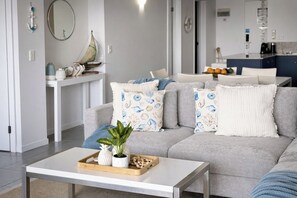 A modern living room with a grey sofa, a white coffee table, and a small side table with decorative items.