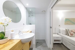 A modern bathroom with a large mirror, a sink, and a shower.